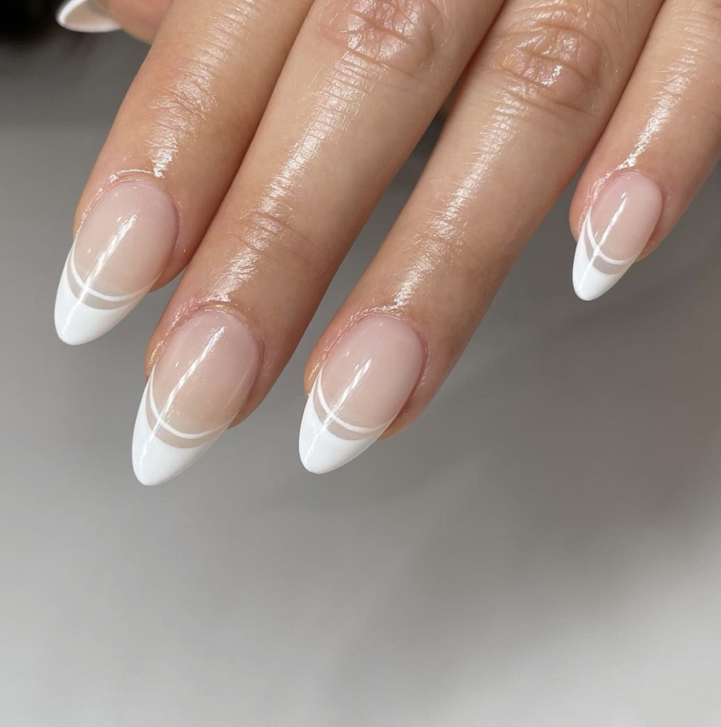 Close-up of nails with white double French tips on a light beige base.